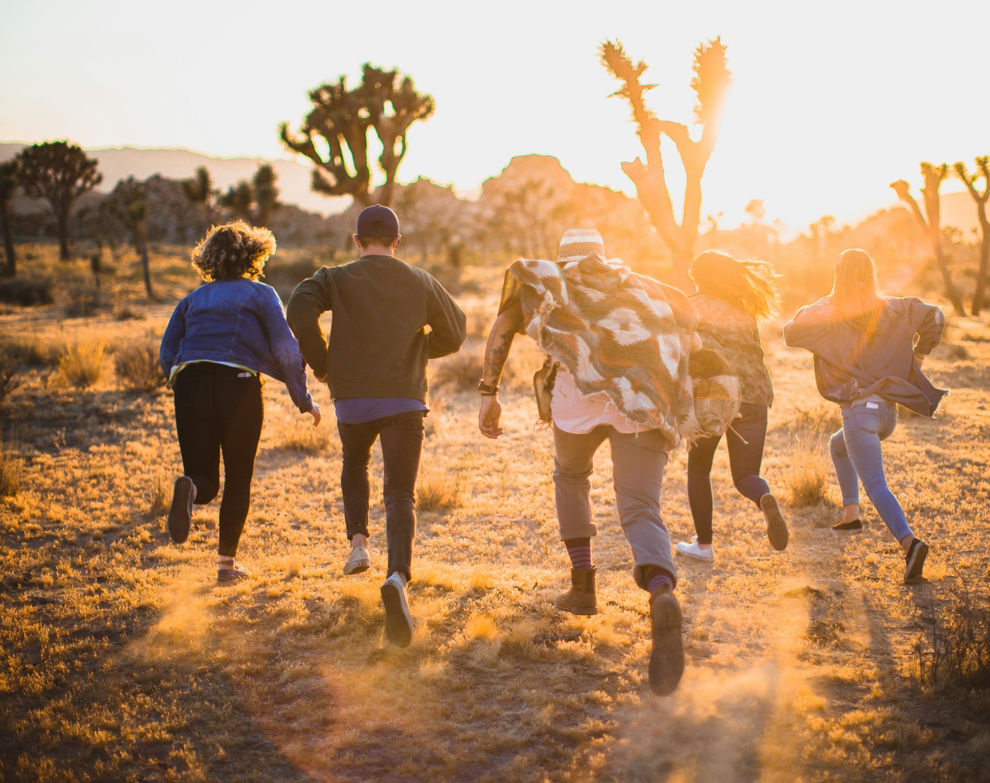 Children running across a field at sunset